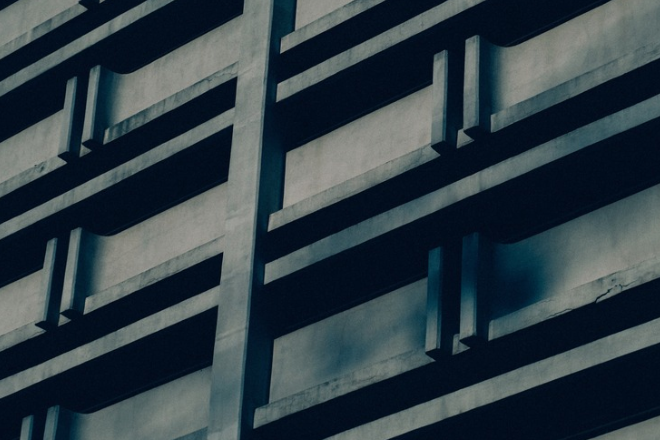 Blue-toned concrete office building facade with deep recessed balconies, representing UAE small businesses and Small Business Relief